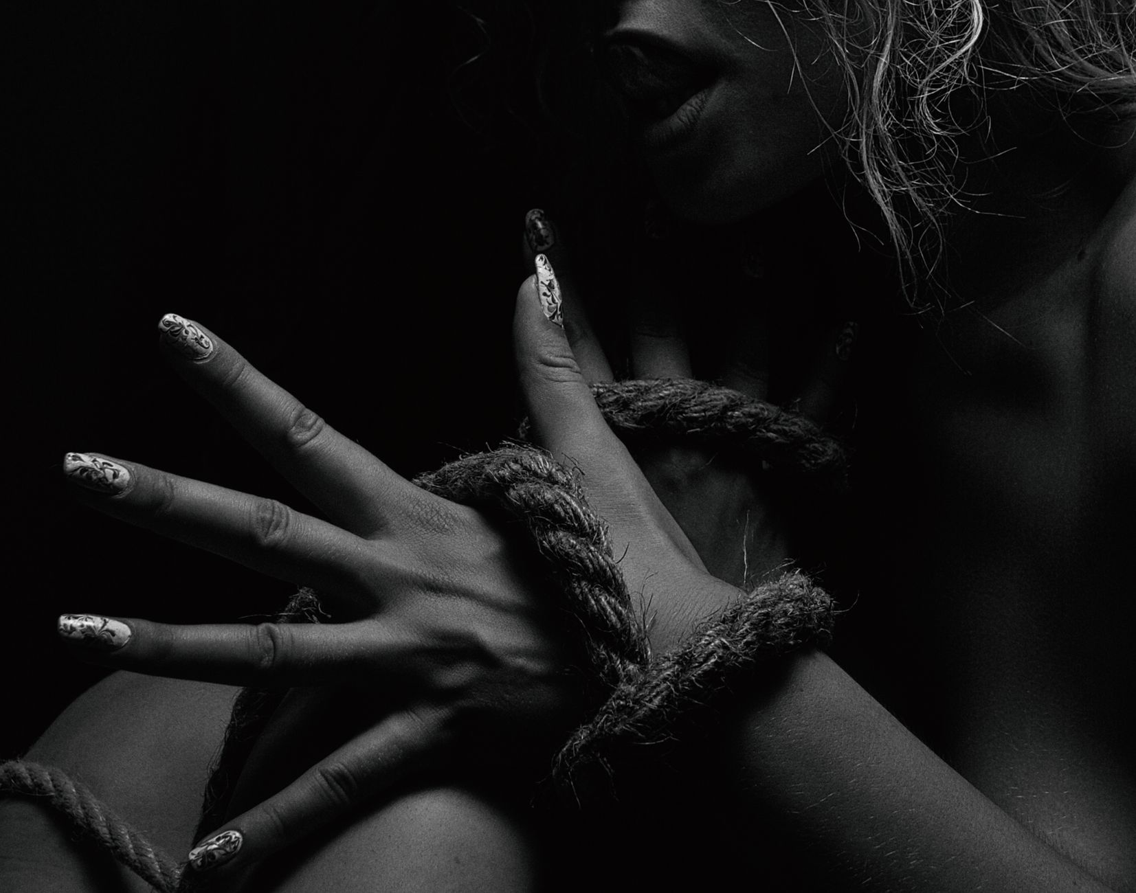 Dramatic black and white photo of a hand entwined with rope, capturing a powerful, emotional theme.