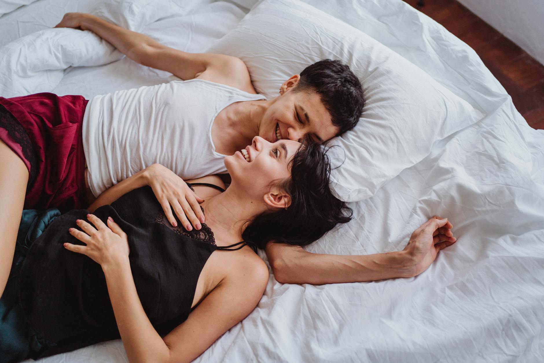 A joyful couple relaxing in bed, sharing intimate and happy moments together.