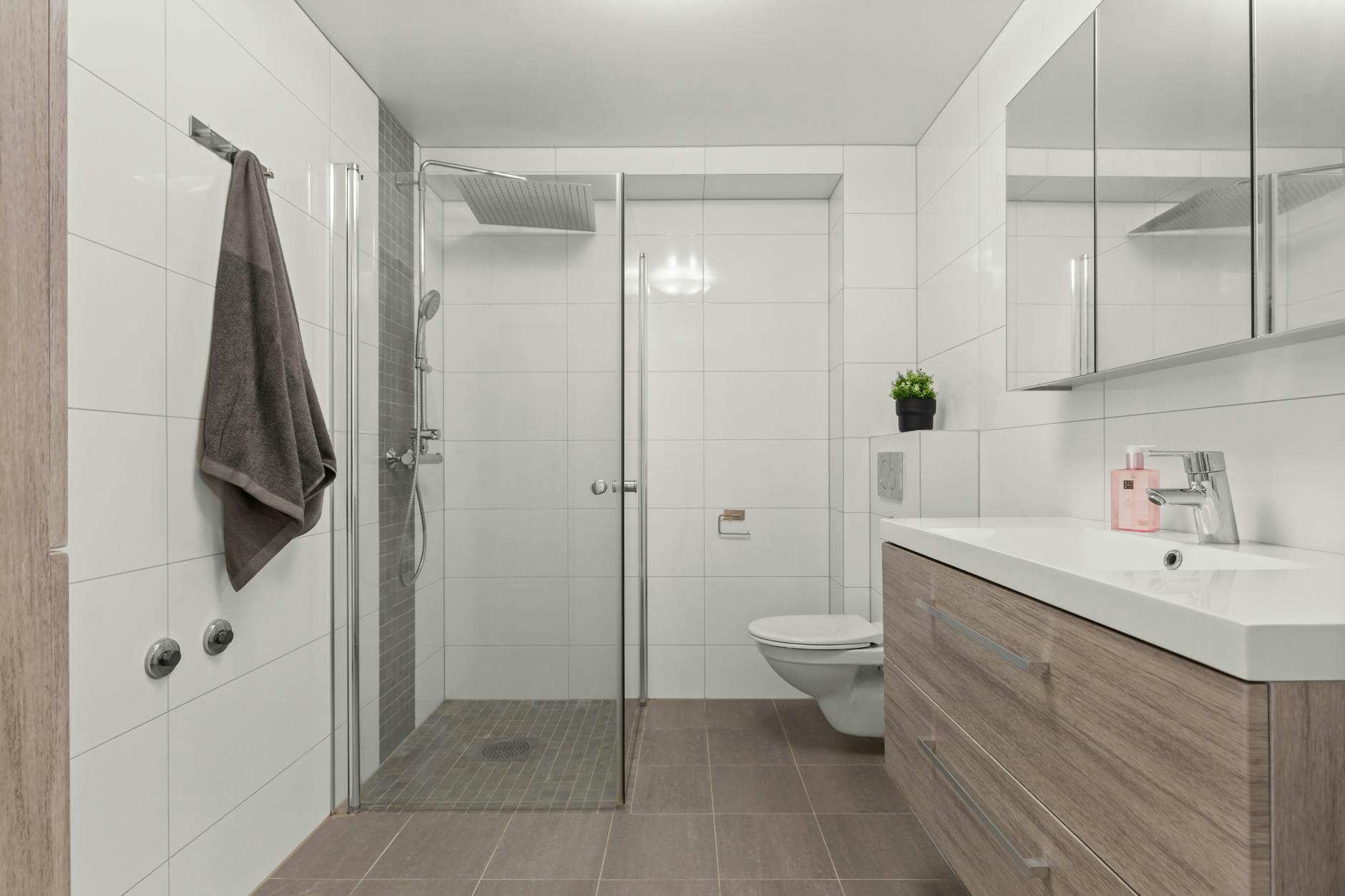 Sleek modern bathroom with glass shower, vanity, and minimalist decor.