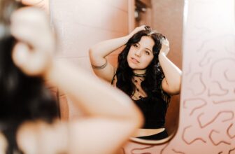 a woman standing in front of a mirror brushing her hair