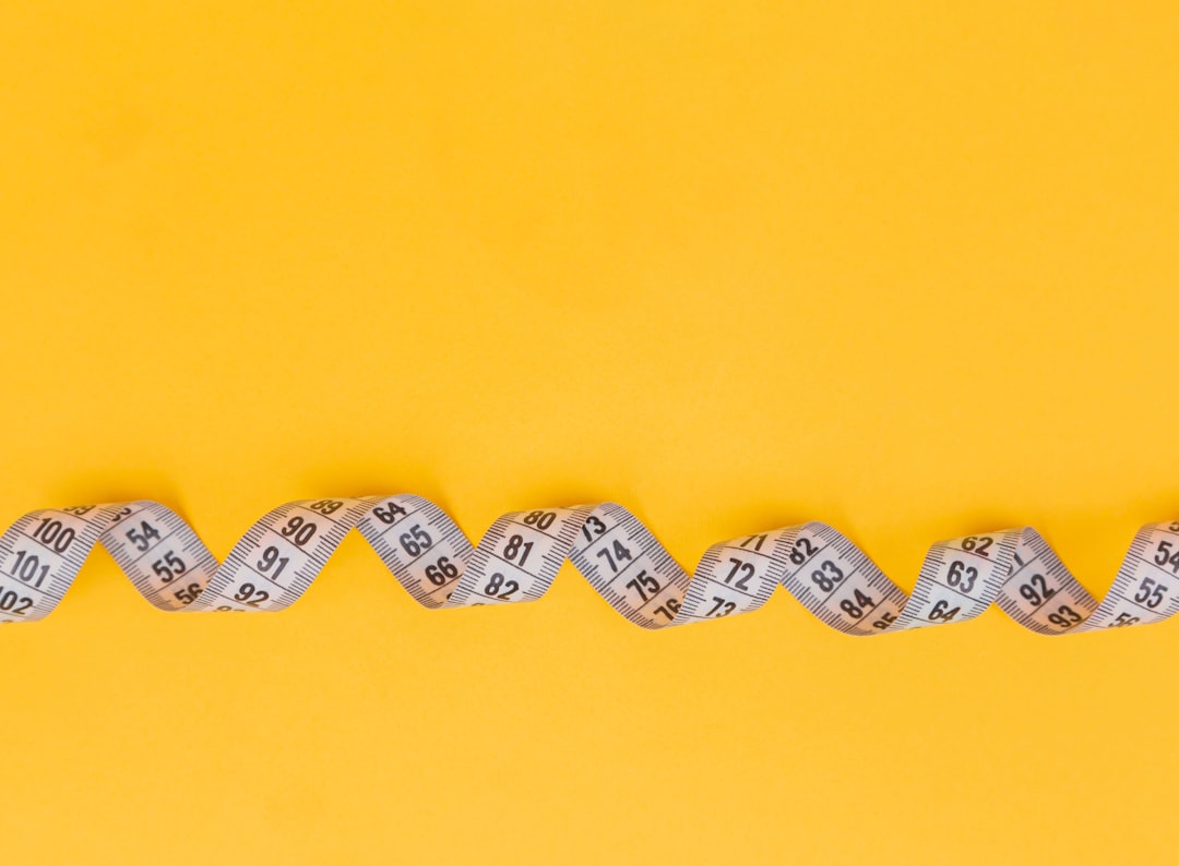 White measuring tape on a yellow background. Diet. Slimming. Obesity. Place for an inscription. Weight loss marathon. Advertising. Top view. The close plan