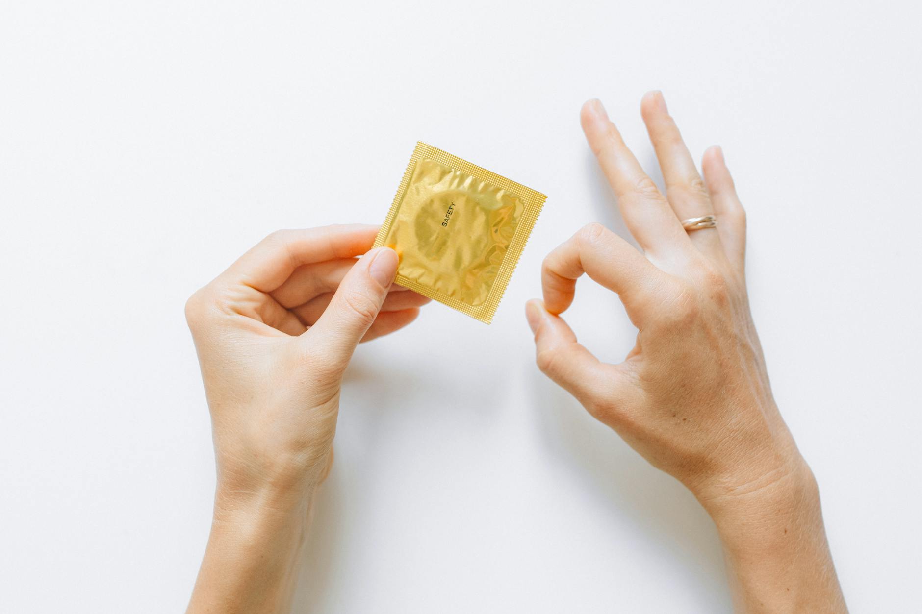 Golden condom packet held by hand, emphasizing safe sex and contraception.