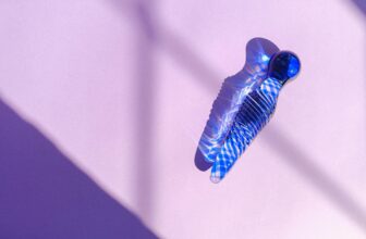 Blue glass object casting intricate shadows on a pastel pink background, creating an abstract aesthetic