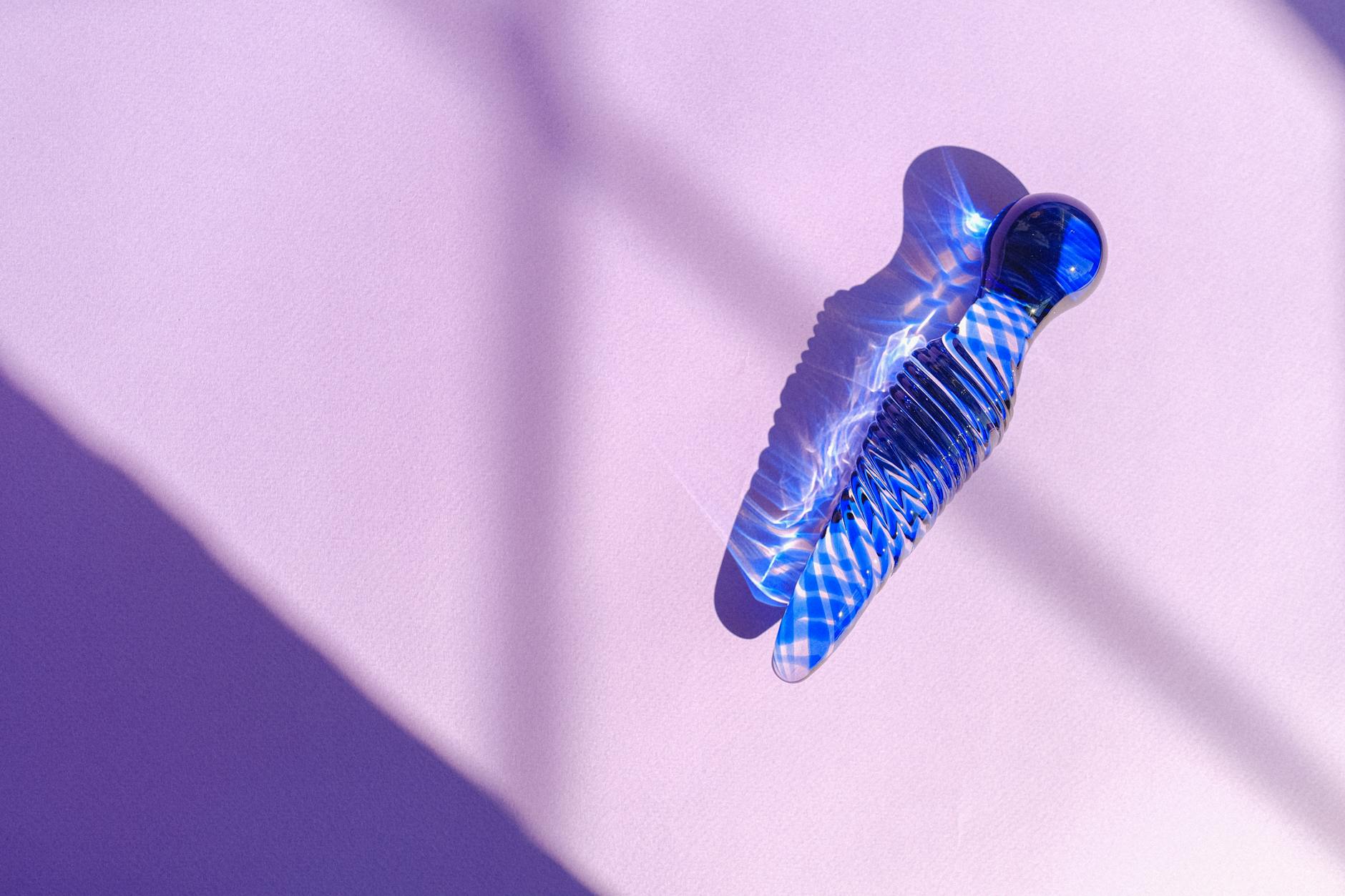 Blue glass object casting intricate shadows on a pastel pink background, creating an abstract aesthetic