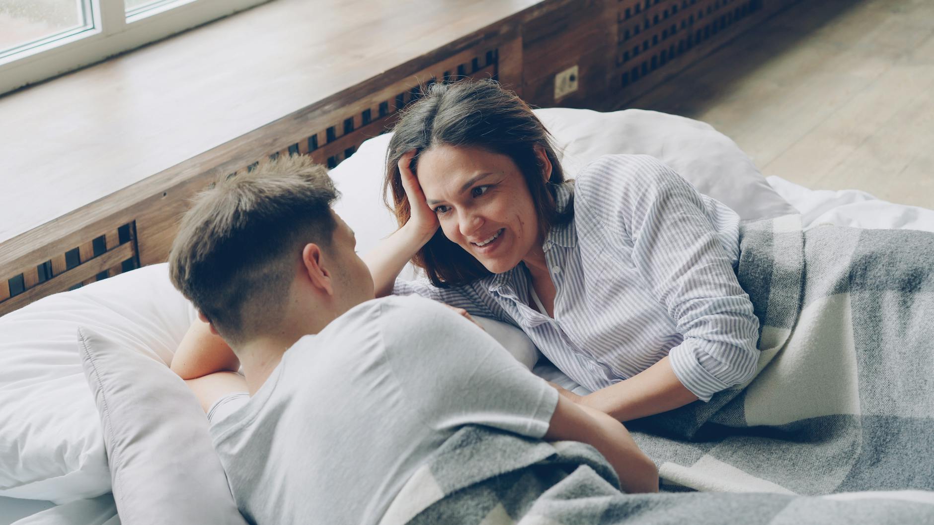 A couple relaxing in bed, sharing a cozy moment filled with warmth and intimacy