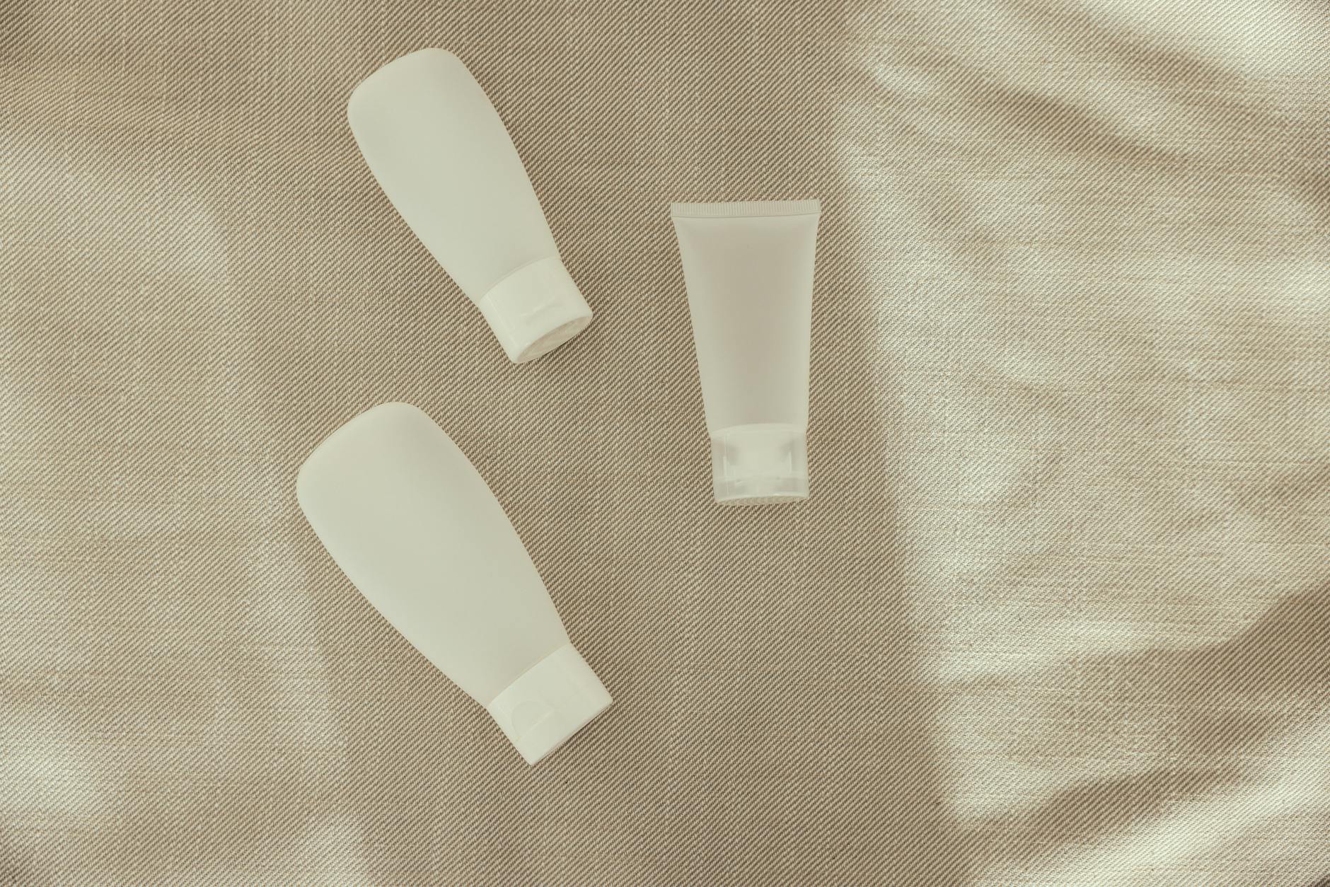 Flat lay image of minimalist plastic squeeze bottles on a textured surface