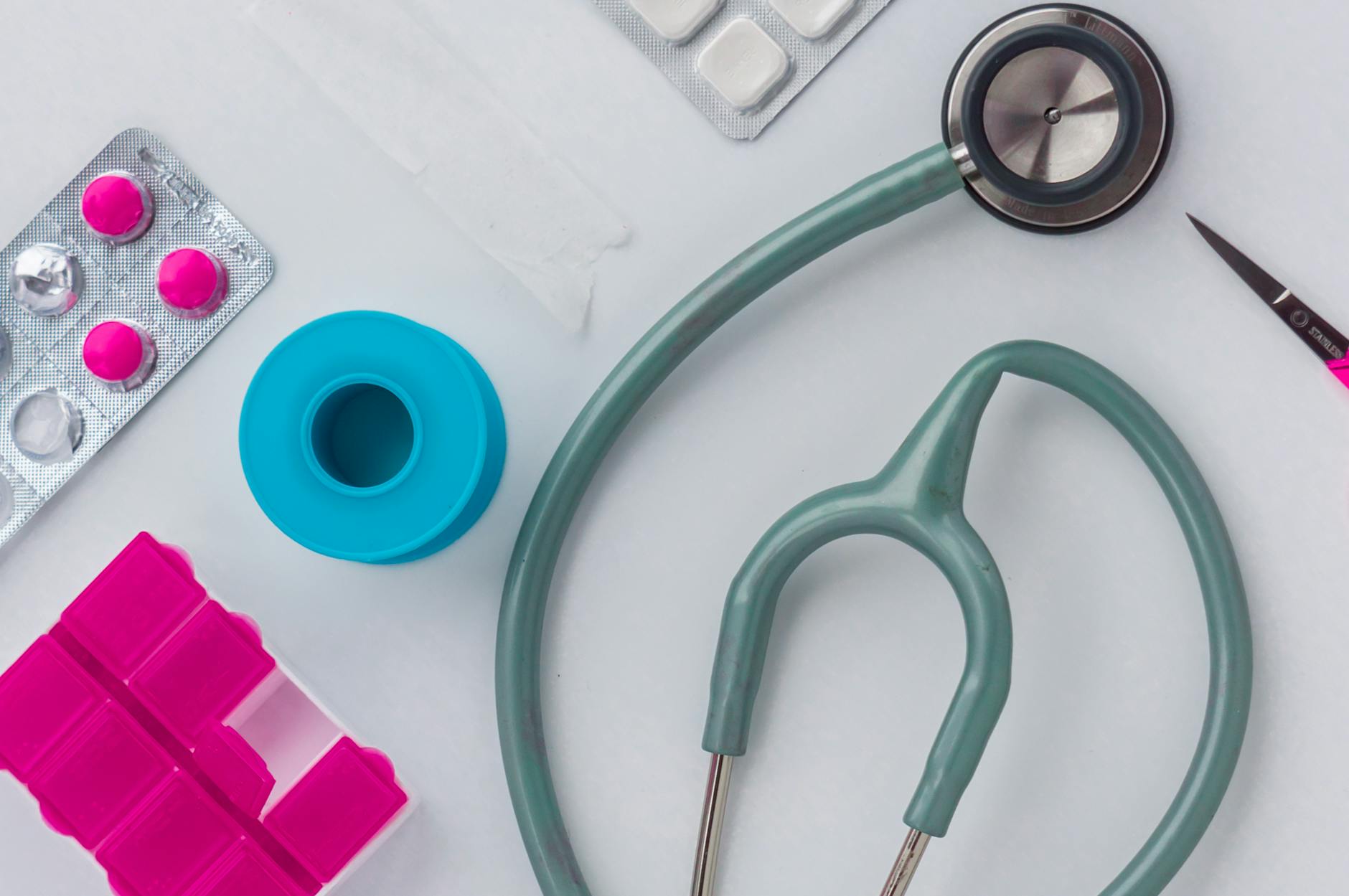 Overhead shot of medical supplies including stethoscope, pills, and scissors