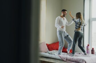 Young beautiful and loving couple dancing rocknroll dance on bed in morning at home