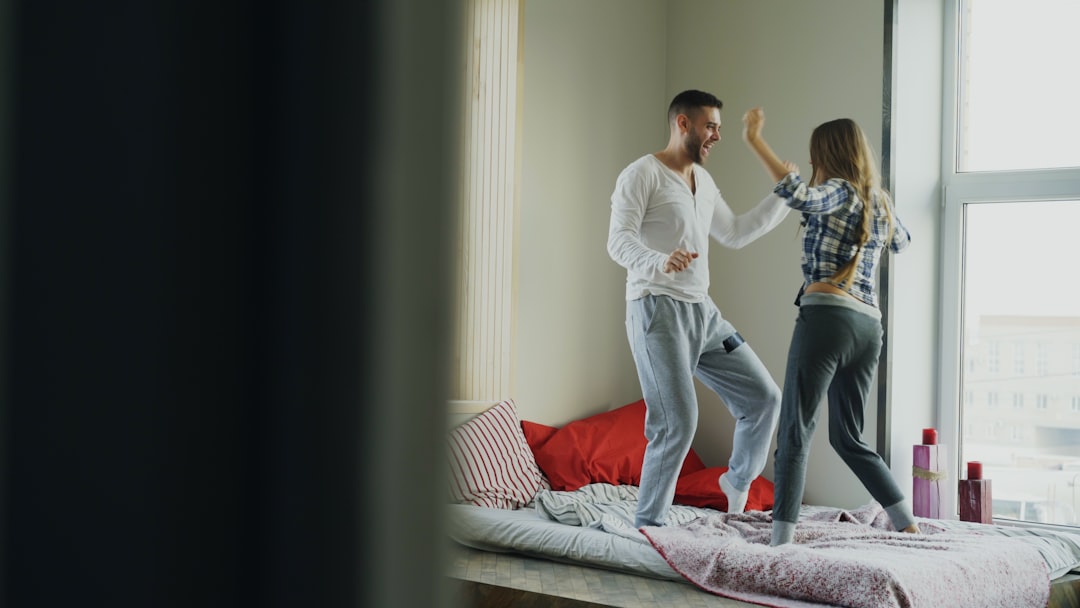Young beautiful and loving couple dancing rocknroll dance on bed in morning at home