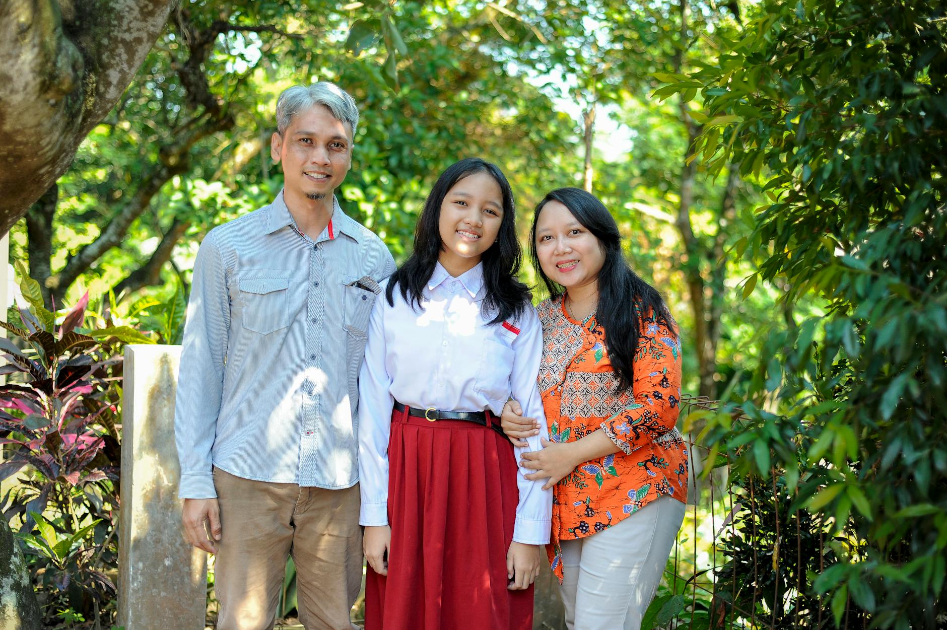 A smiling family enjoys togetherness in a lush green park during a sunny summer day