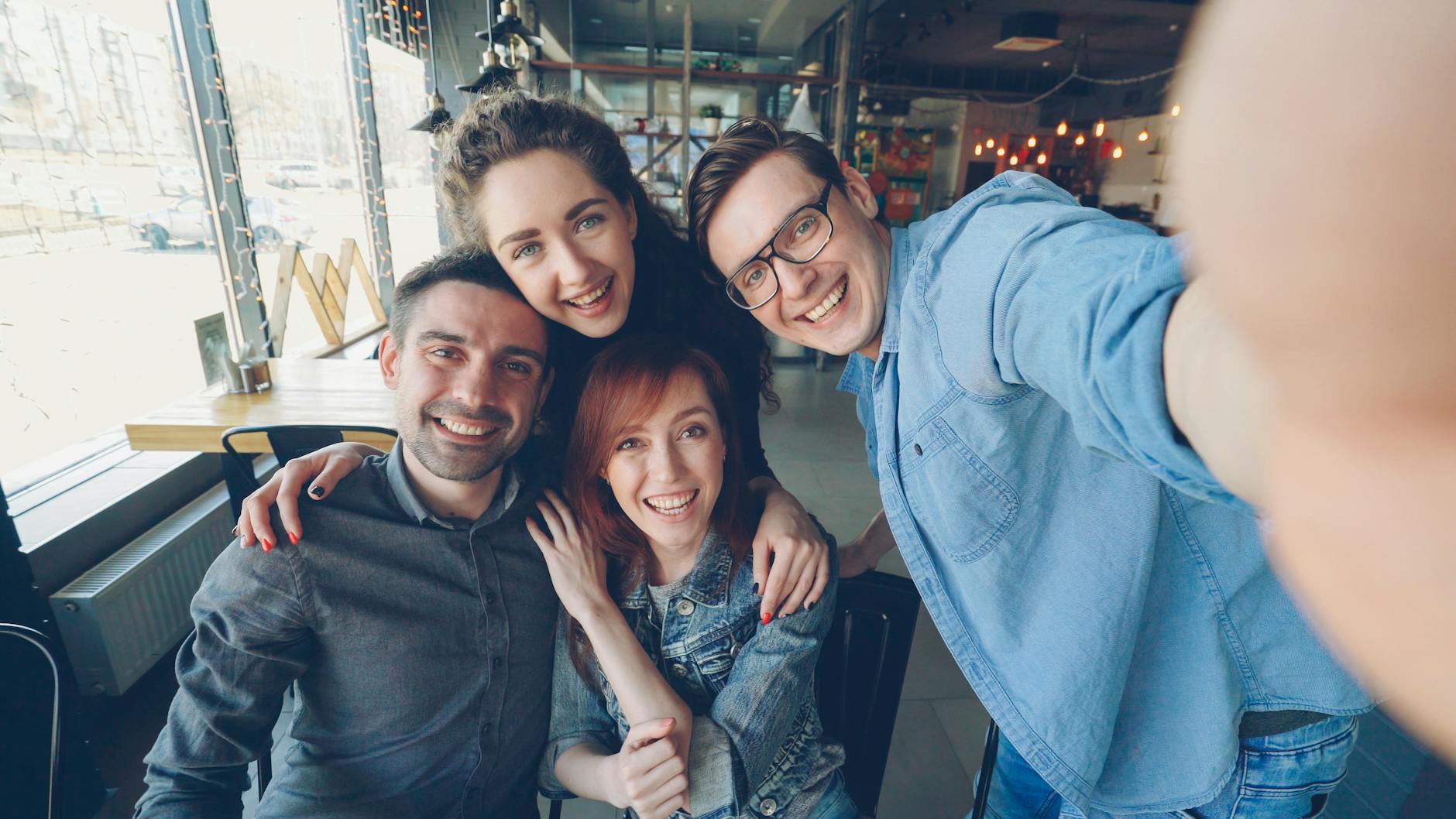 Happy group of friends taking a selfie together in a cozy cafe setting